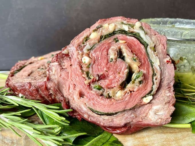 Genseden bavette rollade op een plank met verse kruiden en een potje pesto op de achtergrond.