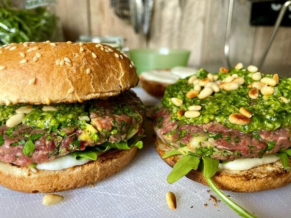 Twee raw burgers belegd met mozzarella, tartaar pesto en pijnboompitten